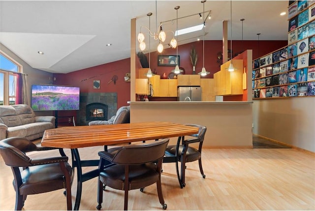 dining area featuring light hardwood / wood-style floors, lofted ceiling, a notable chandelier, and a fireplace