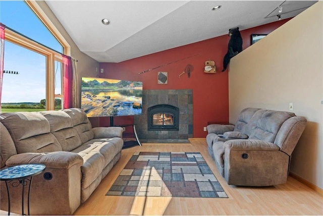 living room featuring a tiled fireplace, light hardwood / wood-style flooring, and vaulted ceiling