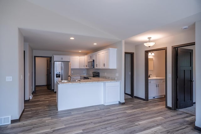 kitchen with appliances with stainless steel finishes, white cabinets, and light hardwood / wood-style floors