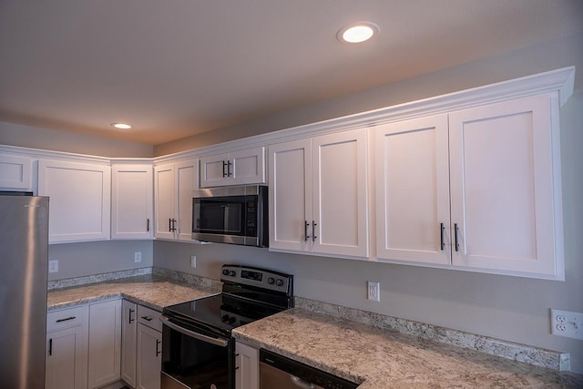 kitchen with appliances with stainless steel finishes, light stone counters, and white cabinets