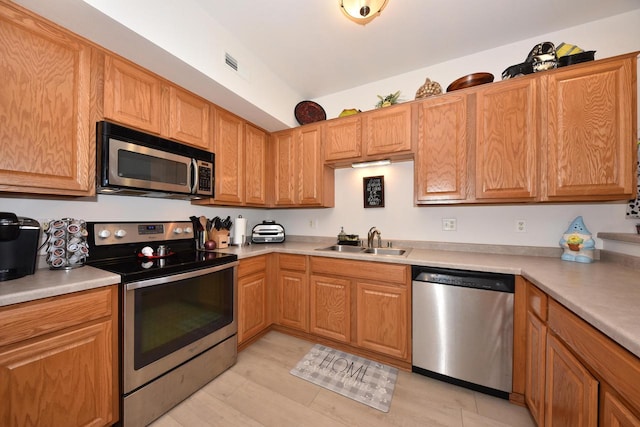 kitchen with appliances with stainless steel finishes, sink, and light wood-type flooring