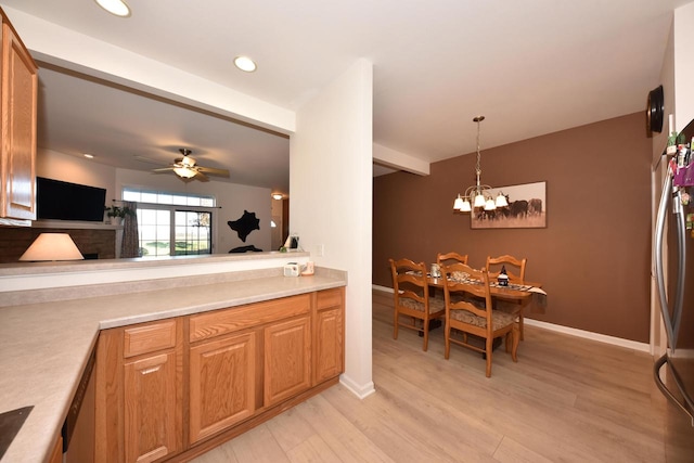 kitchen featuring pendant lighting, appliances with stainless steel finishes, ceiling fan with notable chandelier, and light hardwood / wood-style floors