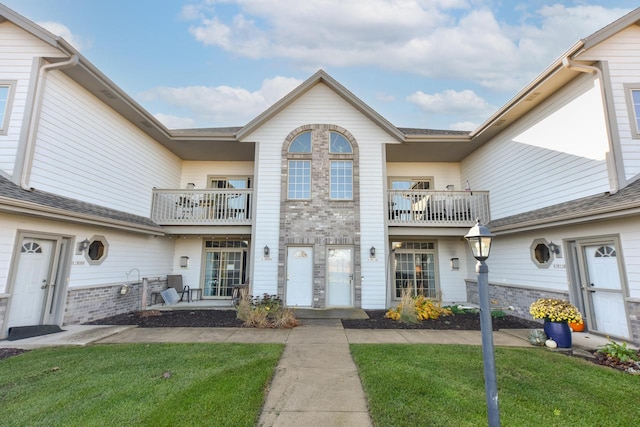 view of front facade with a balcony and a front lawn