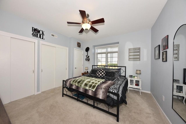 carpeted bedroom featuring two closets and ceiling fan