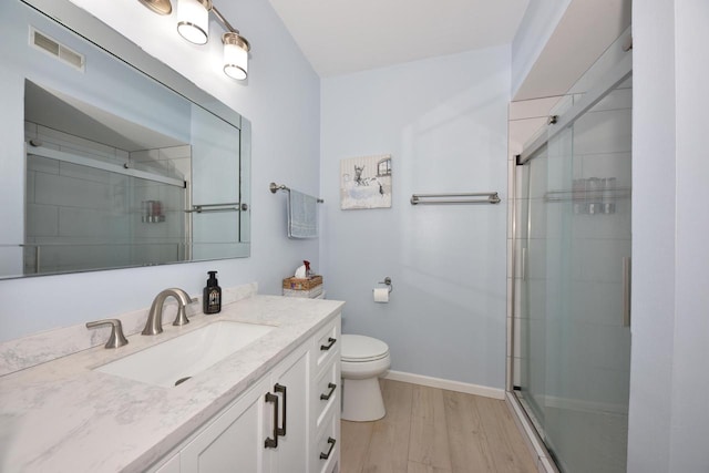 bathroom featuring vanity, wood-type flooring, toilet, and an enclosed shower