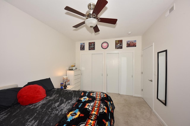 carpeted bedroom with multiple closets and ceiling fan