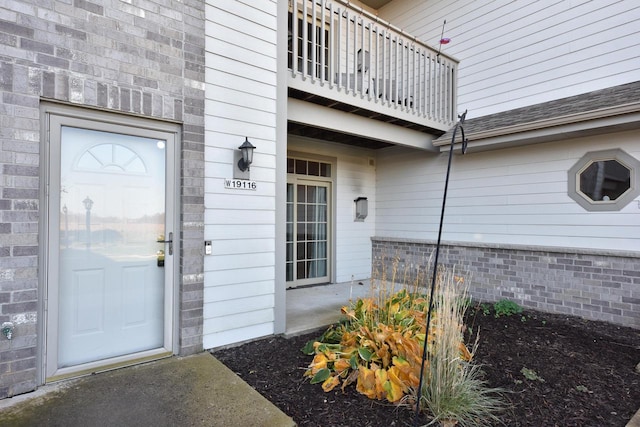 view of exterior entry with a balcony