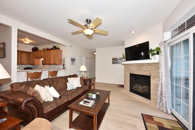 living room featuring light hardwood / wood-style floors, a wealth of natural light, a fireplace, and ceiling fan