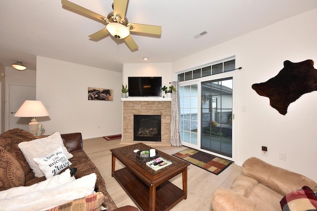 living room with a fireplace, light hardwood / wood-style floors, and ceiling fan