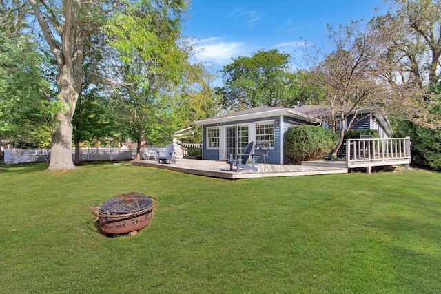 back of house featuring a yard, a deck, and a fire pit