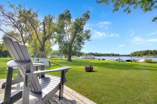 exterior space with a deck with water view, a lawn, and a fire pit