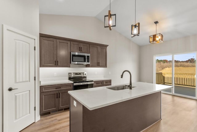 kitchen featuring sink, hanging light fixtures, stainless steel appliances, vaulted ceiling, and light hardwood / wood-style flooring