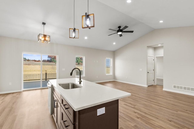 kitchen with sink, vaulted ceiling, decorative light fixtures, and light wood-type flooring