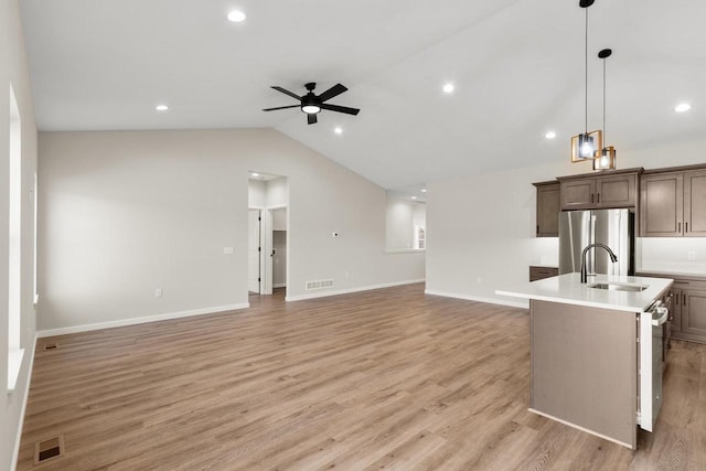 kitchen featuring vaulted ceiling, light wood-type flooring, and an island with sink