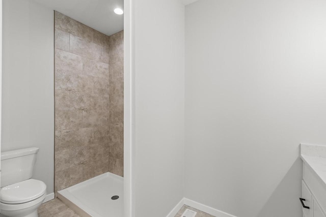 bathroom with vanity, toilet, tile patterned floors, and tiled shower