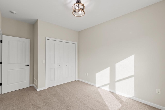 unfurnished bedroom with light colored carpet and a closet