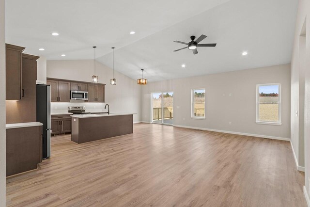 kitchen featuring light hardwood / wood-style floors, stainless steel appliances, a kitchen island with sink, and hanging light fixtures