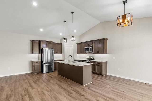 kitchen featuring appliances with stainless steel finishes, light hardwood / wood-style flooring, hanging light fixtures, and vaulted ceiling