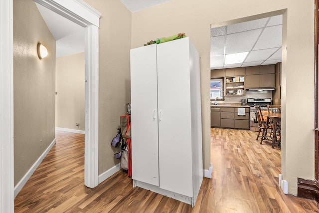 corridor featuring a drop ceiling and light hardwood / wood-style flooring