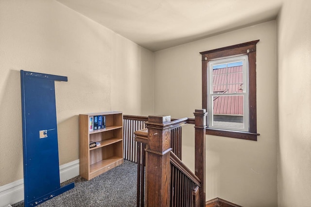 hall with dark colored carpet