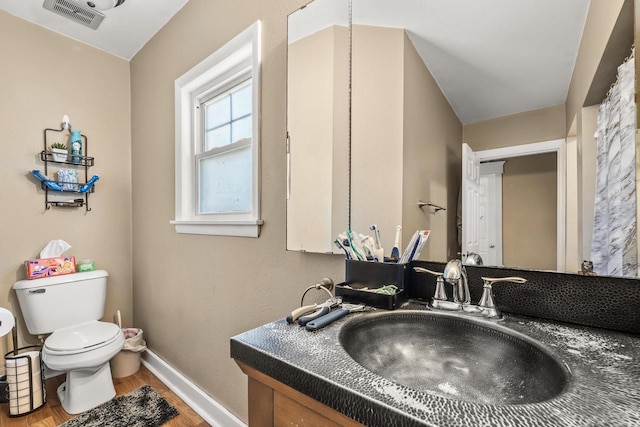 bathroom featuring toilet, hardwood / wood-style floors, vanity, and vaulted ceiling