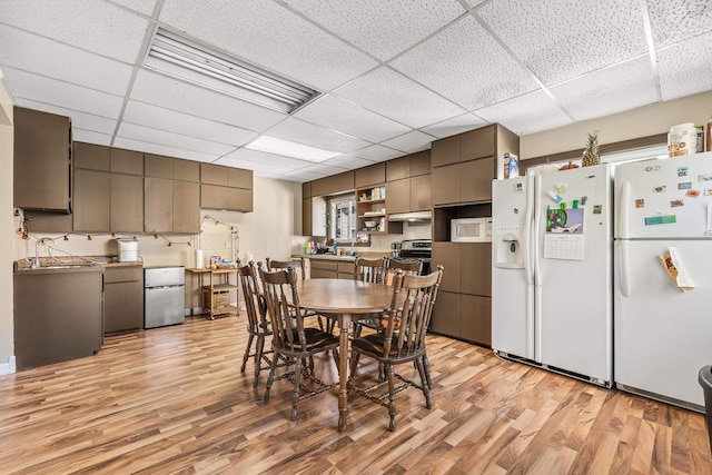 dining space with sink, a drop ceiling, and light hardwood / wood-style flooring