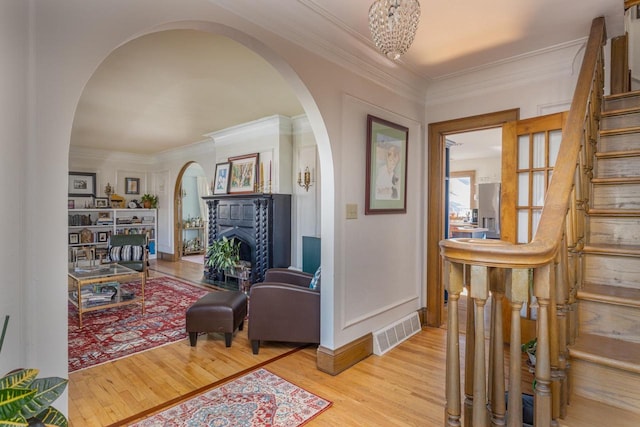 sitting room with ornamental molding, a chandelier, and light wood-type flooring