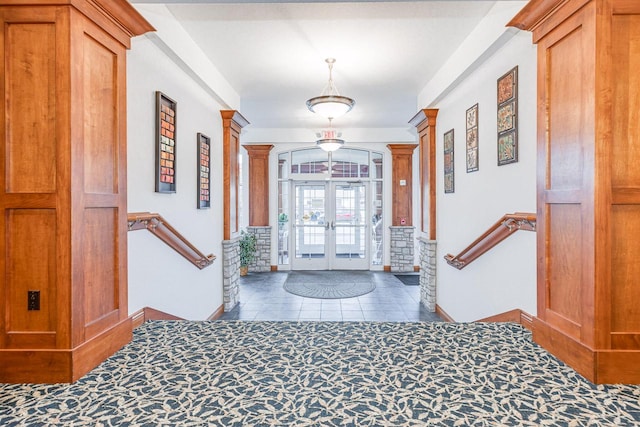 foyer entrance featuring french doors, ornate columns, and dark tile patterned flooring