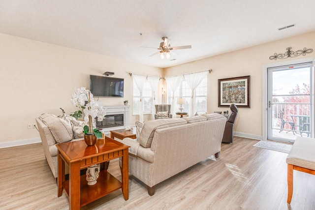 living room with light hardwood / wood-style flooring, ceiling fan, and a wealth of natural light