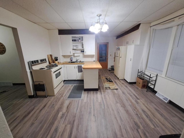 kitchen with a drop ceiling, white appliances, hanging light fixtures, butcher block countertops, and white cabinetry