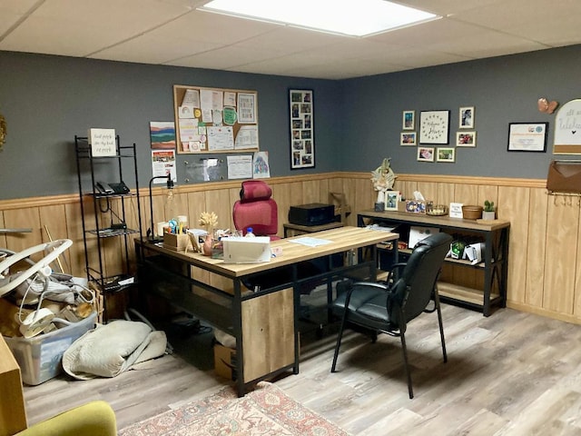 office with a paneled ceiling, wooden walls, and hardwood / wood-style floors