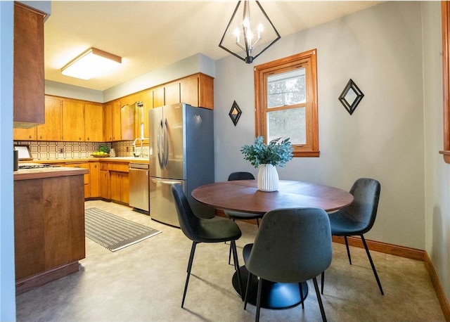 kitchen with decorative backsplash, hanging light fixtures, a chandelier, sink, and stainless steel appliances