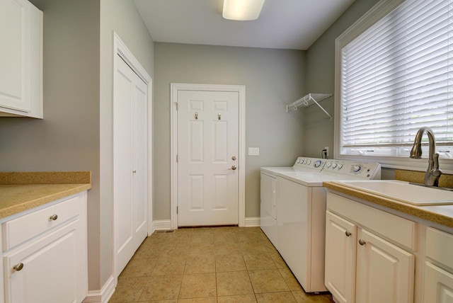 clothes washing area featuring sink, light tile patterned flooring, separate washer and dryer, and cabinets