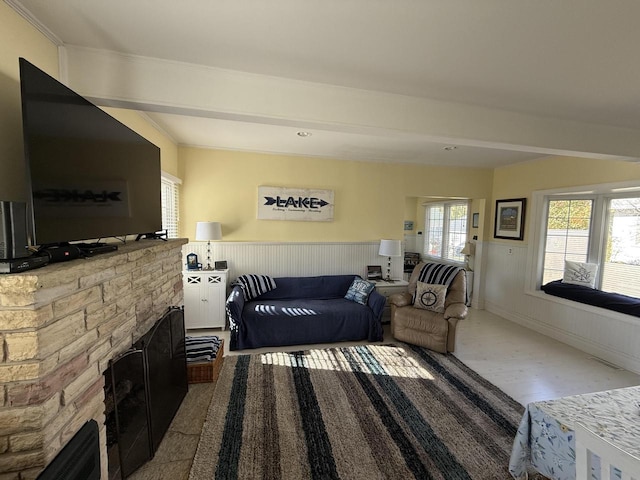 living room with hardwood / wood-style flooring, a stone fireplace, and crown molding