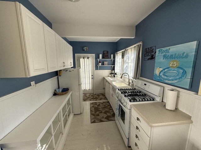 kitchen featuring light hardwood / wood-style floors, white cabinetry, sink, and white appliances