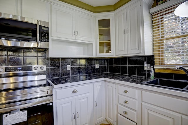 kitchen with appliances with stainless steel finishes, plenty of natural light, and white cabinets