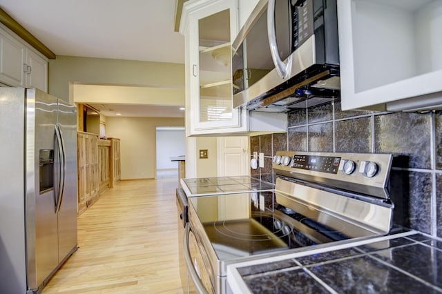 kitchen featuring light hardwood / wood-style floors, decorative backsplash, white cabinets, and stainless steel appliances