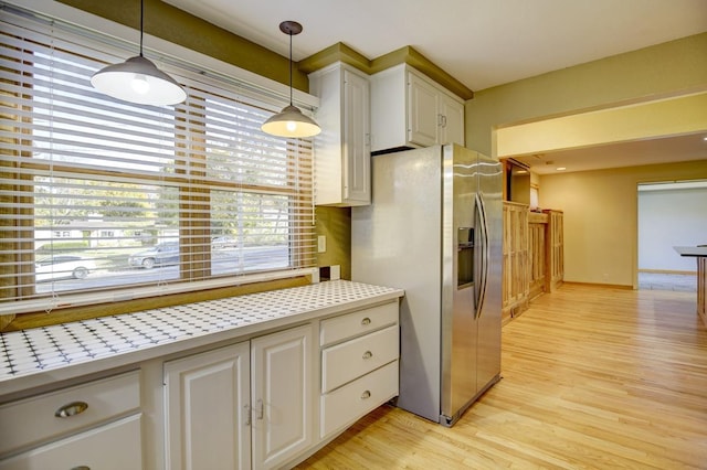 kitchen featuring stainless steel fridge with ice dispenser, decorative light fixtures, light wood-type flooring, and white cabinets