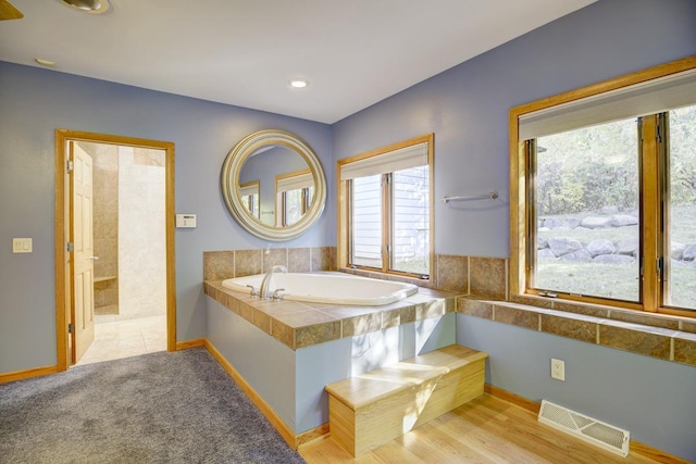 bathroom featuring tiled bath and wood-type flooring