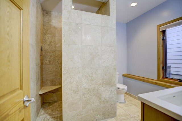 bathroom featuring toilet, vanity, a tile shower, and tile patterned flooring