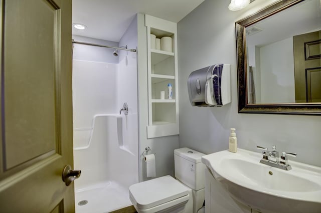 bathroom featuring toilet, walk in shower, and sink