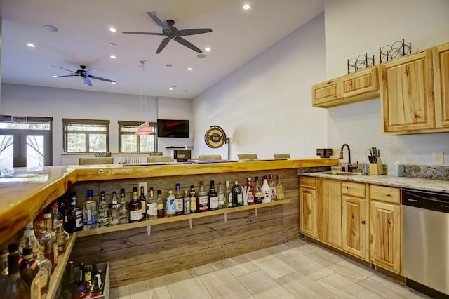 kitchen featuring light brown cabinets, ceiling fan, stainless steel dishwasher, pendant lighting, and sink