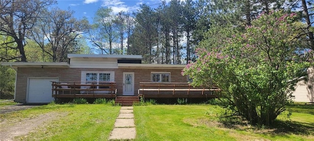 rear view of property featuring a yard, a wooden deck, and a garage