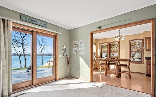 entryway with light wood-type flooring, a chandelier, and a water view