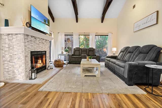 living room with high vaulted ceiling, beamed ceiling, light wood-type flooring, and a fireplace