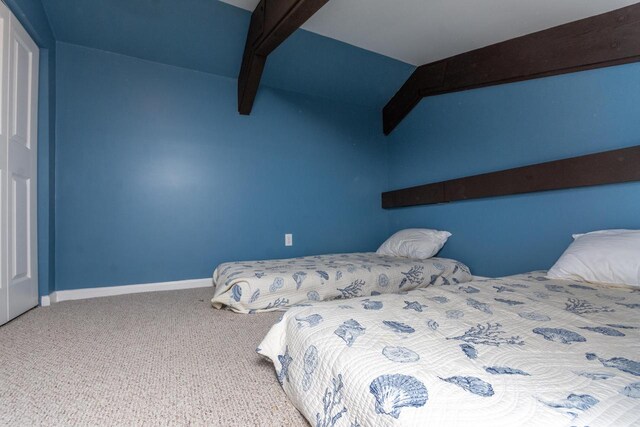 carpeted bedroom with beamed ceiling