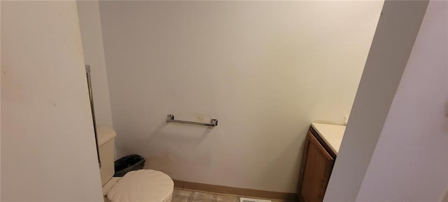 bathroom with baseboards, toilet, and vanity