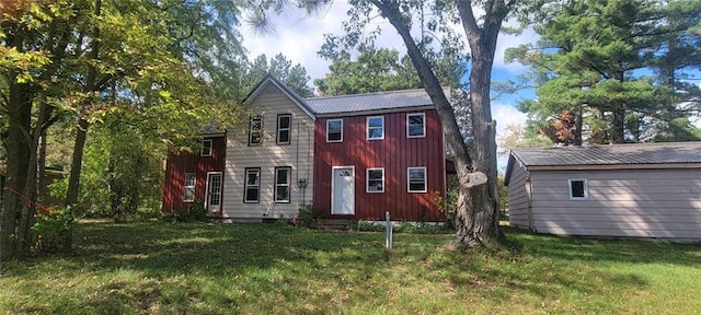 back of property featuring metal roof, a lawn, and board and batten siding