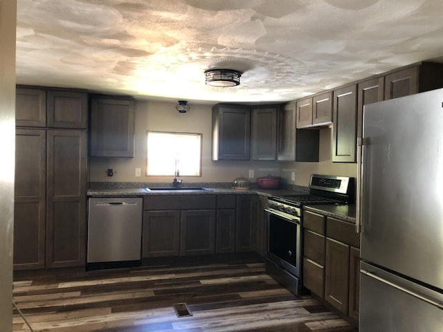 kitchen with dark wood-type flooring, stainless steel appliances, a textured ceiling, and sink