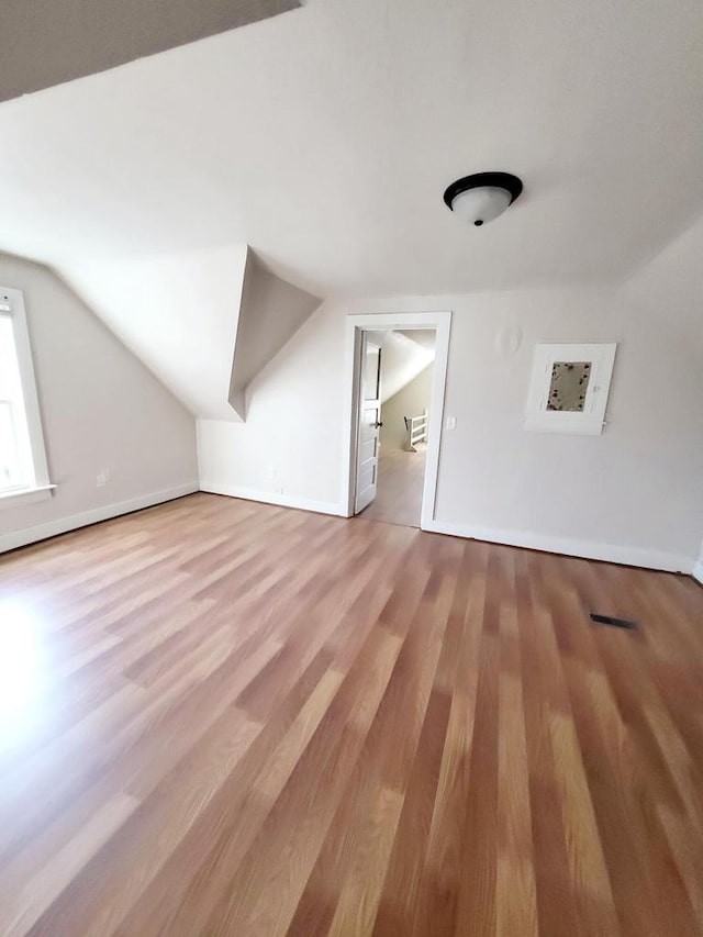 bonus room with vaulted ceiling and light wood-type flooring